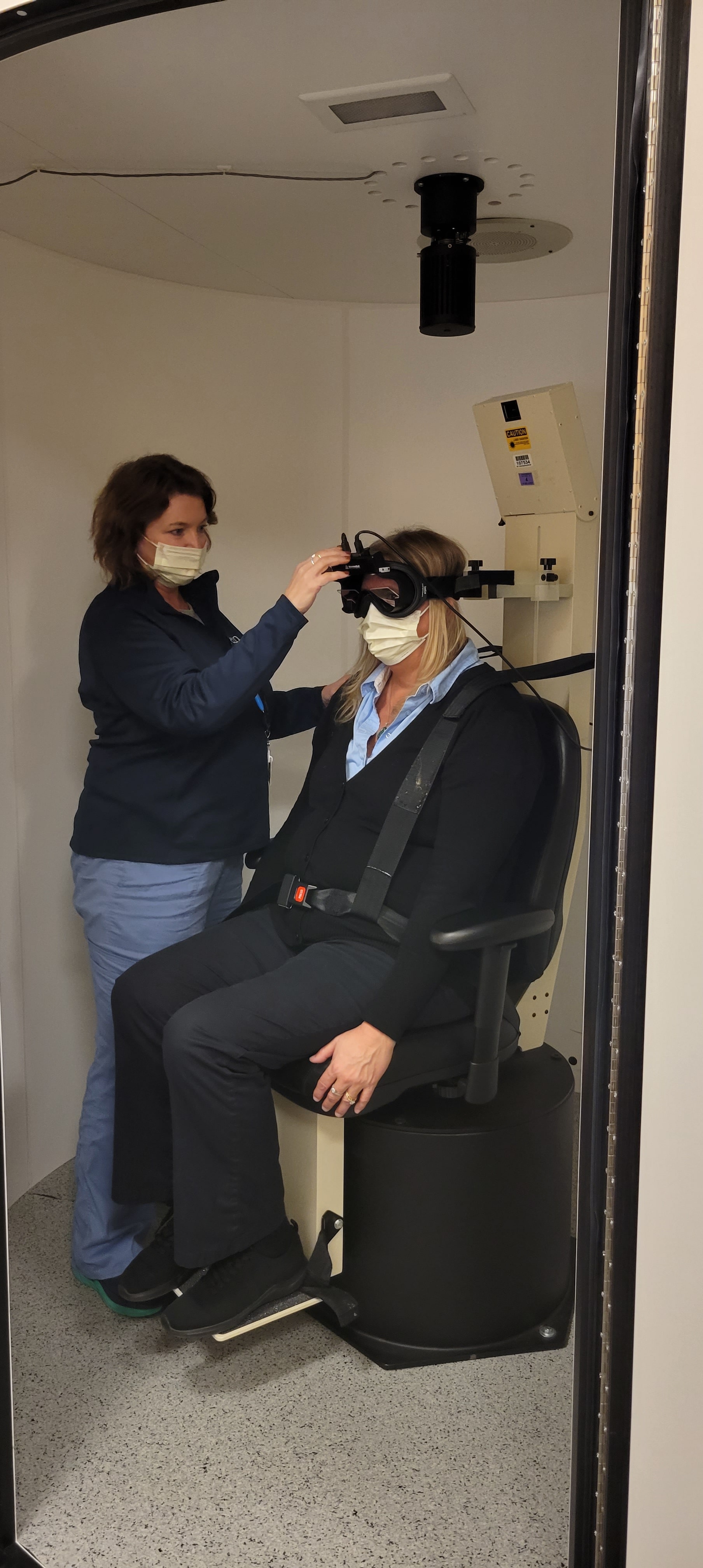 Sherrie Davis demonstrates equipment used at the Penn Balance and Dizziness Center sitting down